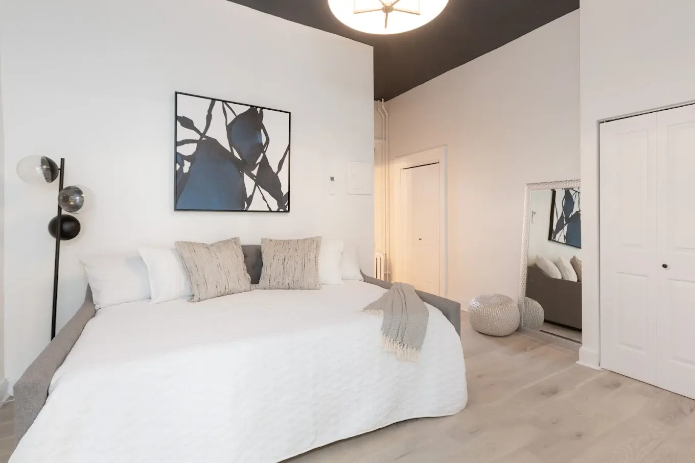 A bedroom with a bed, a lamp, and a painting on the wall.